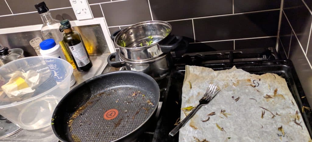 messy kitchen bench with dirty pan, pots, bowl and tray